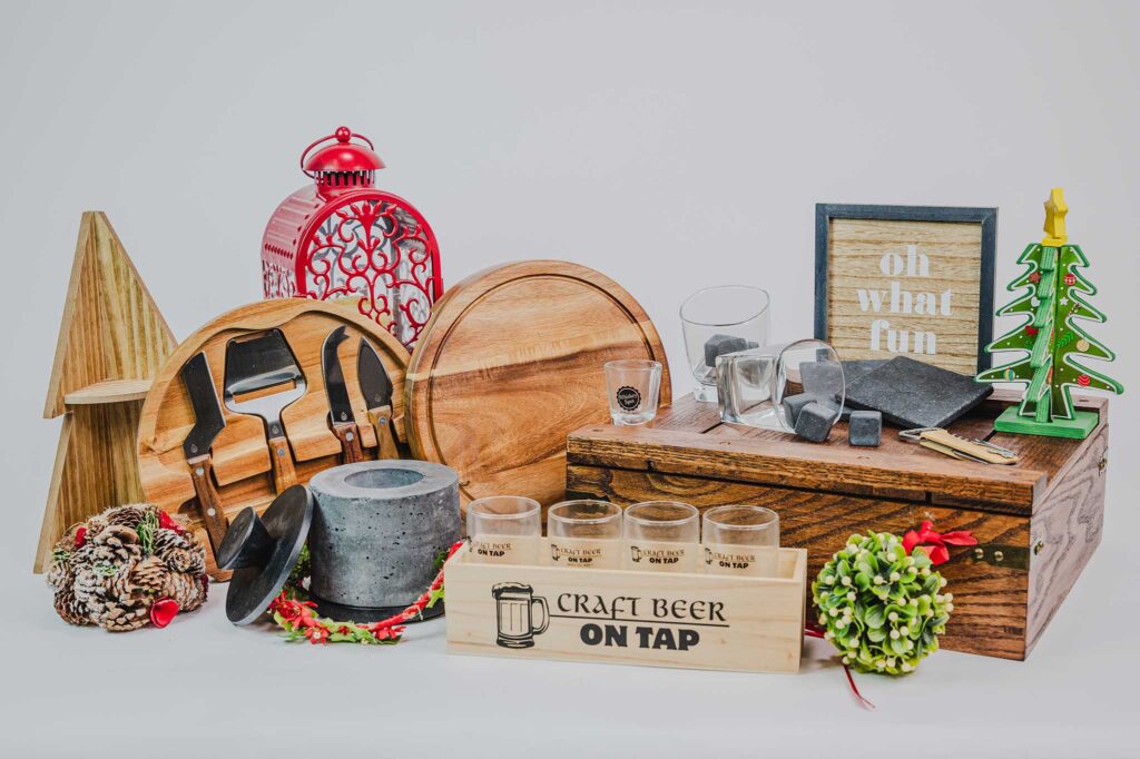 A holiday gift bundle that contains a wooden container of beer glasses, a charcuteries knife set, whiskey glasses and stone cubes and coasters.