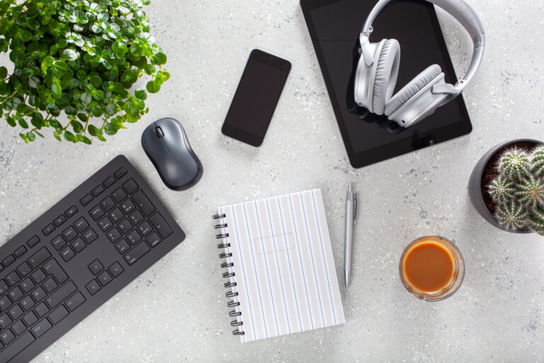 Home office desk with keyboard computer, smartphone, notebook, houseplants, workspace at home.