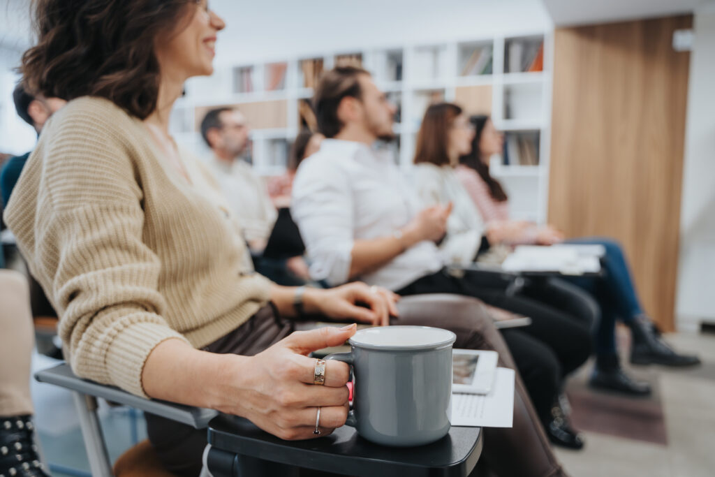 Group meeting where a woman is holding a coffee mug.