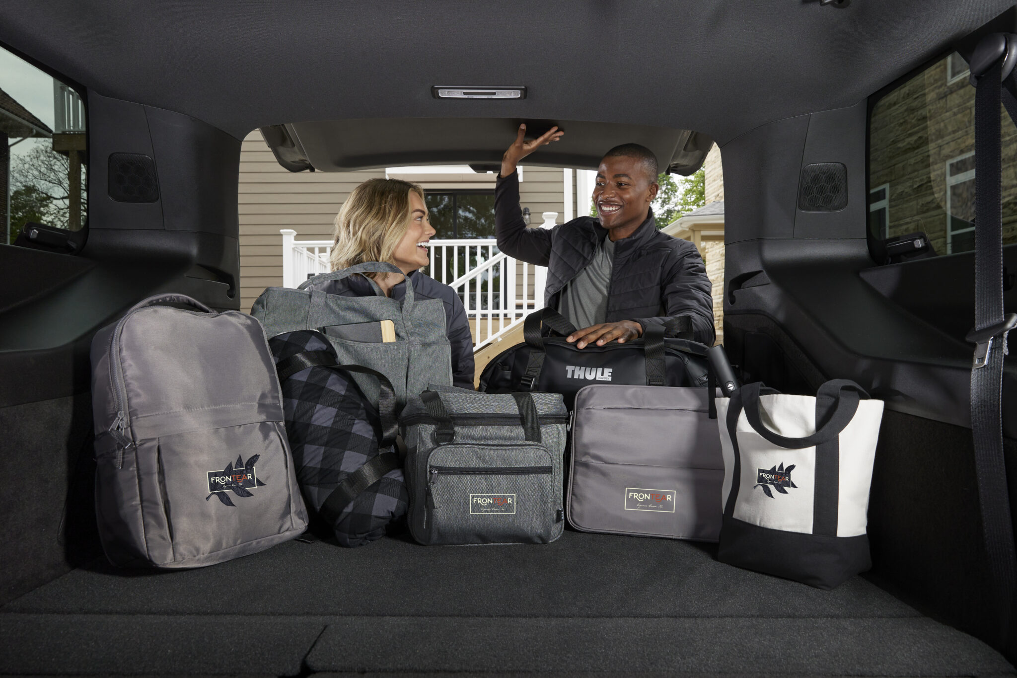 A woman and man placing different types of bags in the trunk of an SUV.