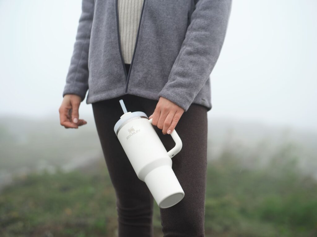 A man holding a white stanley tumbler outside.