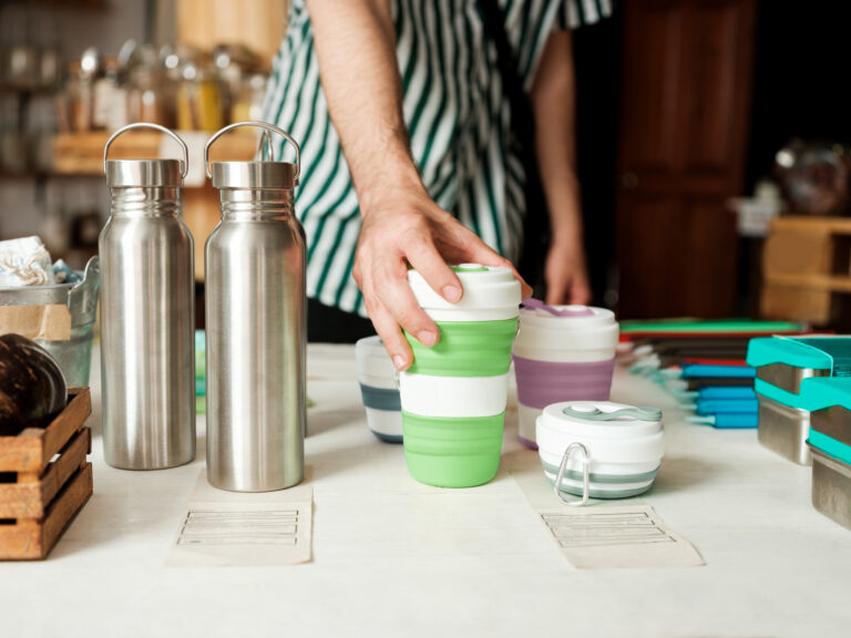 Man over a counter holding reusable bottle.