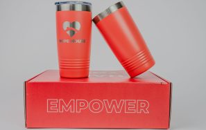 A custom gift box with the words Empower and Serve on it and two tumblers placed on top.